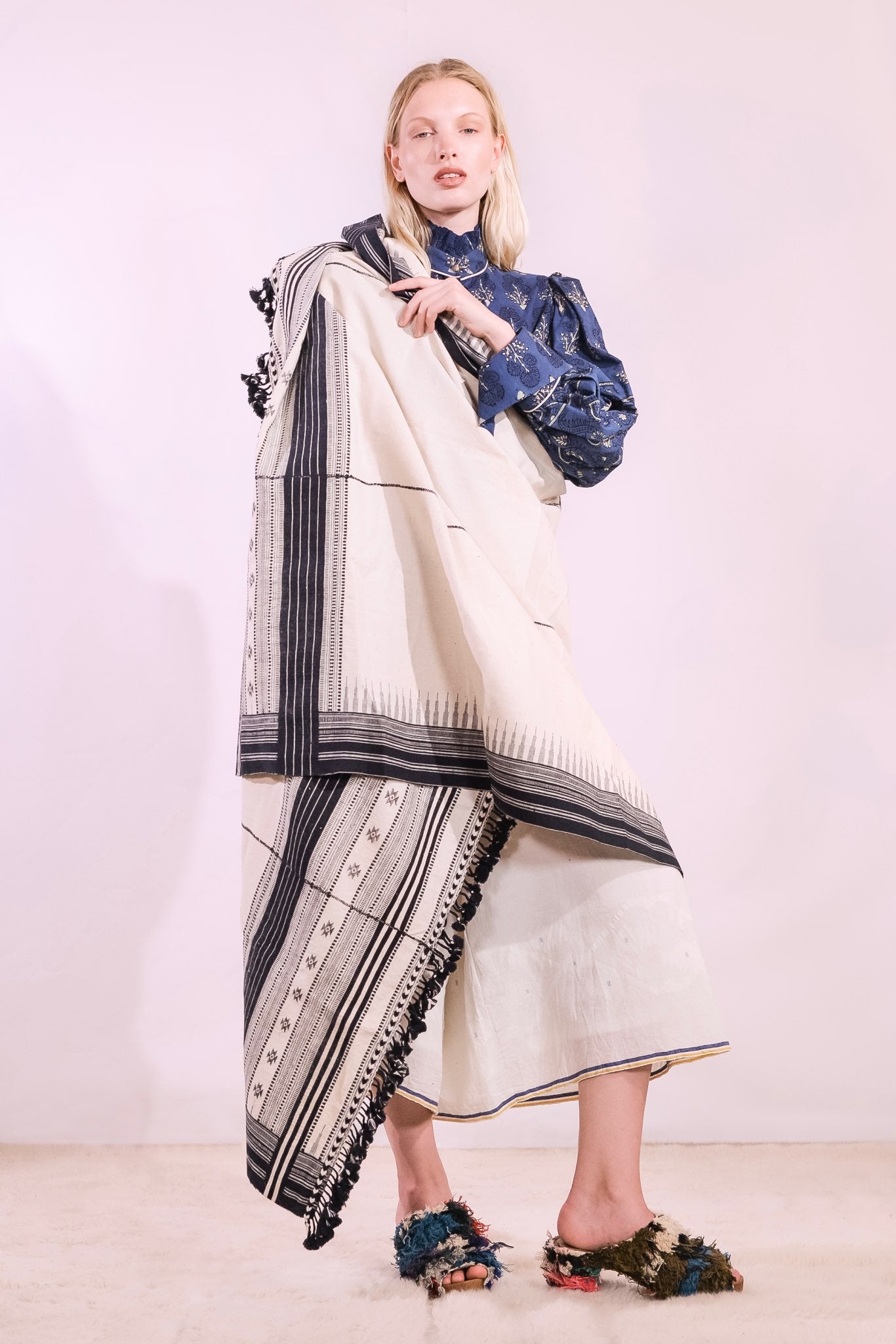 Model is holding the Ananta handwoven kala cotton throw by House of Woven Stories - made from handspun yarn with embroidered panels, crafted in Kutch, India by master weaver Shamji Vankar.