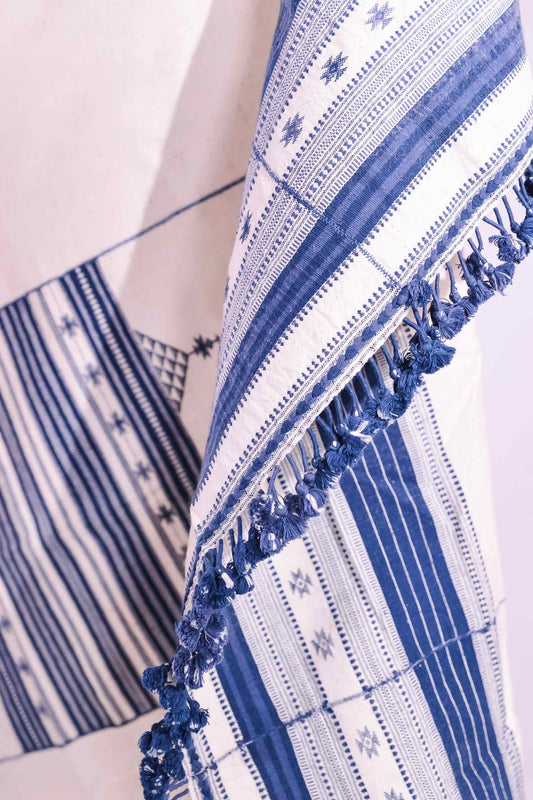 Handwoven kala cotton throw with embroidered panels by Shamji Vankar Vishram Valji, crafted in Bhujodi, India. Made from handspun yarn for a rich, textured feel. A heritage piece curated by House of Woven Stories, blending tradition, sustainability, and artisan craftsmanship. Available at House of Woven Stories.
