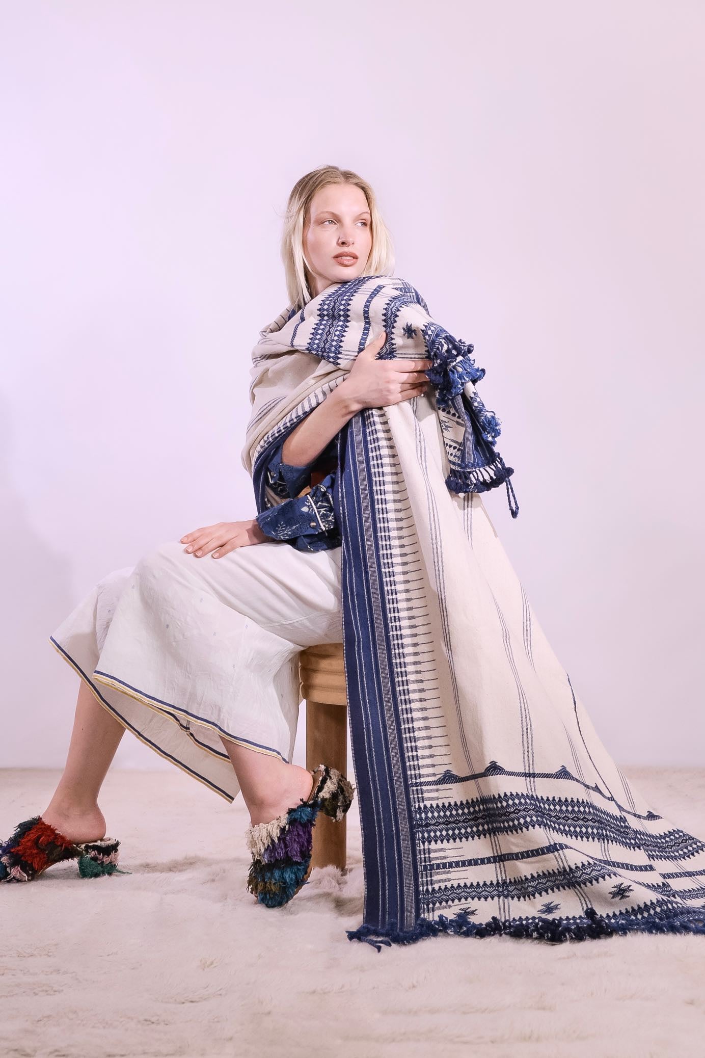 Handwoven kala cotton throw with embroidered panels by Shamji Vankar Vishram Valji, crafted in Bhujodi, India. Made from handspun yarn for a rich, textured feel. A heritage piece curated by House of Woven Stories, blending tradition, sustainability, and artisan craftsmanship. Available at House of Woven Stories.