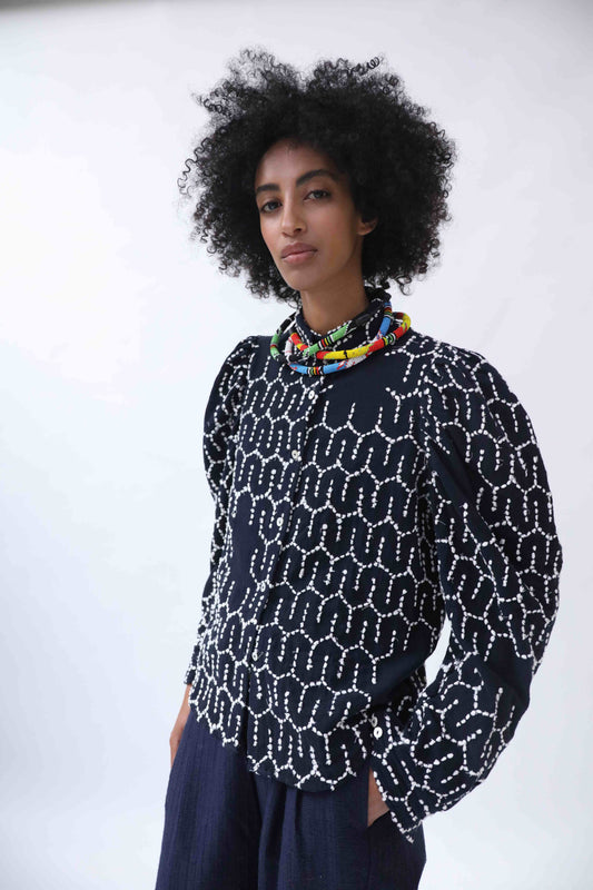 Structured puff-sleeve blouse with sharp collars and Paiwand’s signature upcycled embroidery on organic indigo-dyed cotton, handcrafted in India combining traditional craftsmanship with sustainable, modern fashion.