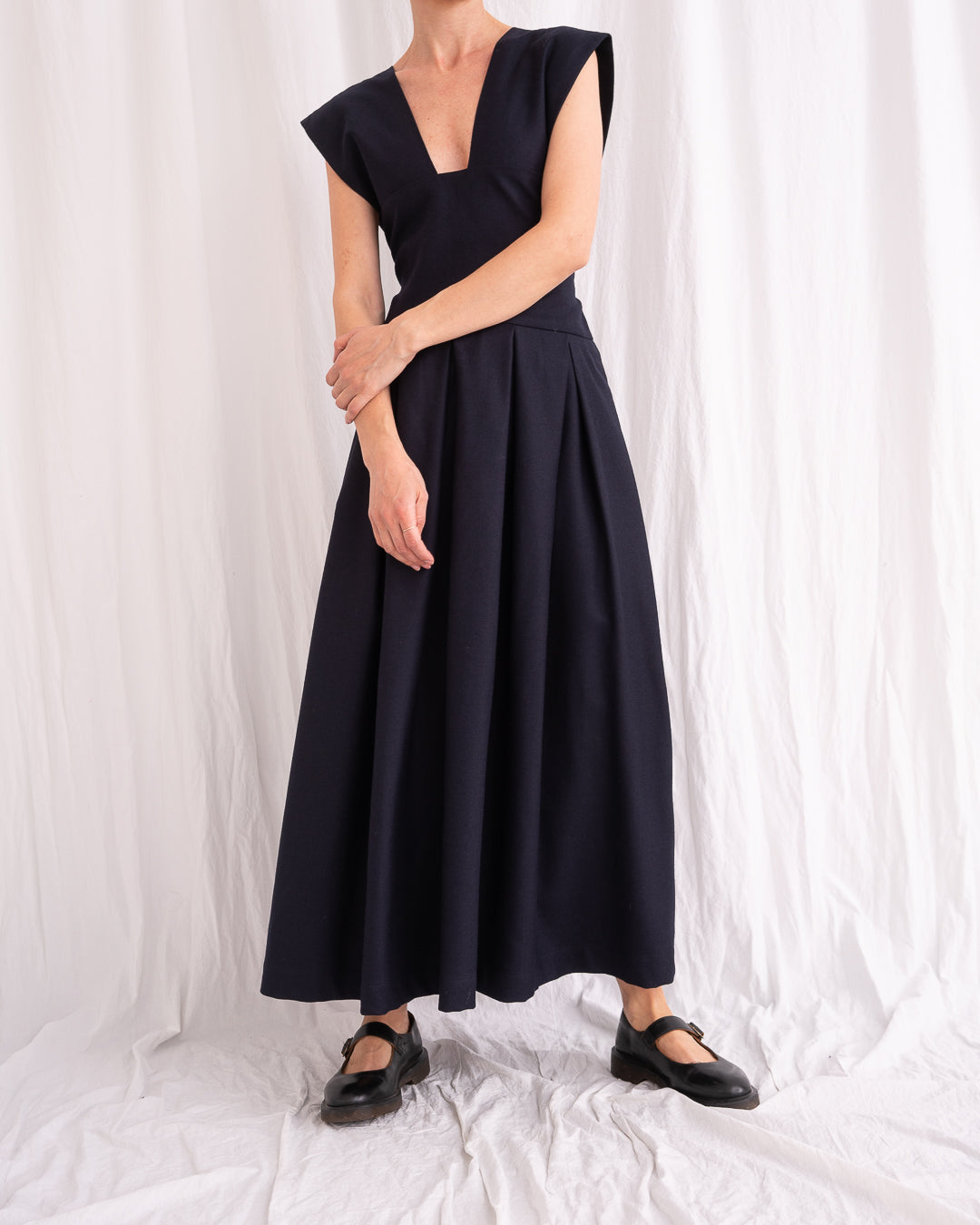 Model is wearing the Sarafan Pure New Wool Dress by Les Vacances d’Irina, a handmade navy merino wool dress with A-line silhouette, tie-back detail, horn buttons, and side pockets, available at House of Woven Stories.