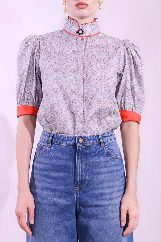 Model is wearing the Mirca Fantasia Liberty Blouse by House of Woven Stories: a lightweight cotton blouse with Liberty floral print, puffed sleeves, bright coral trims, a vintage collar button, and a matching fabric tie for styling.