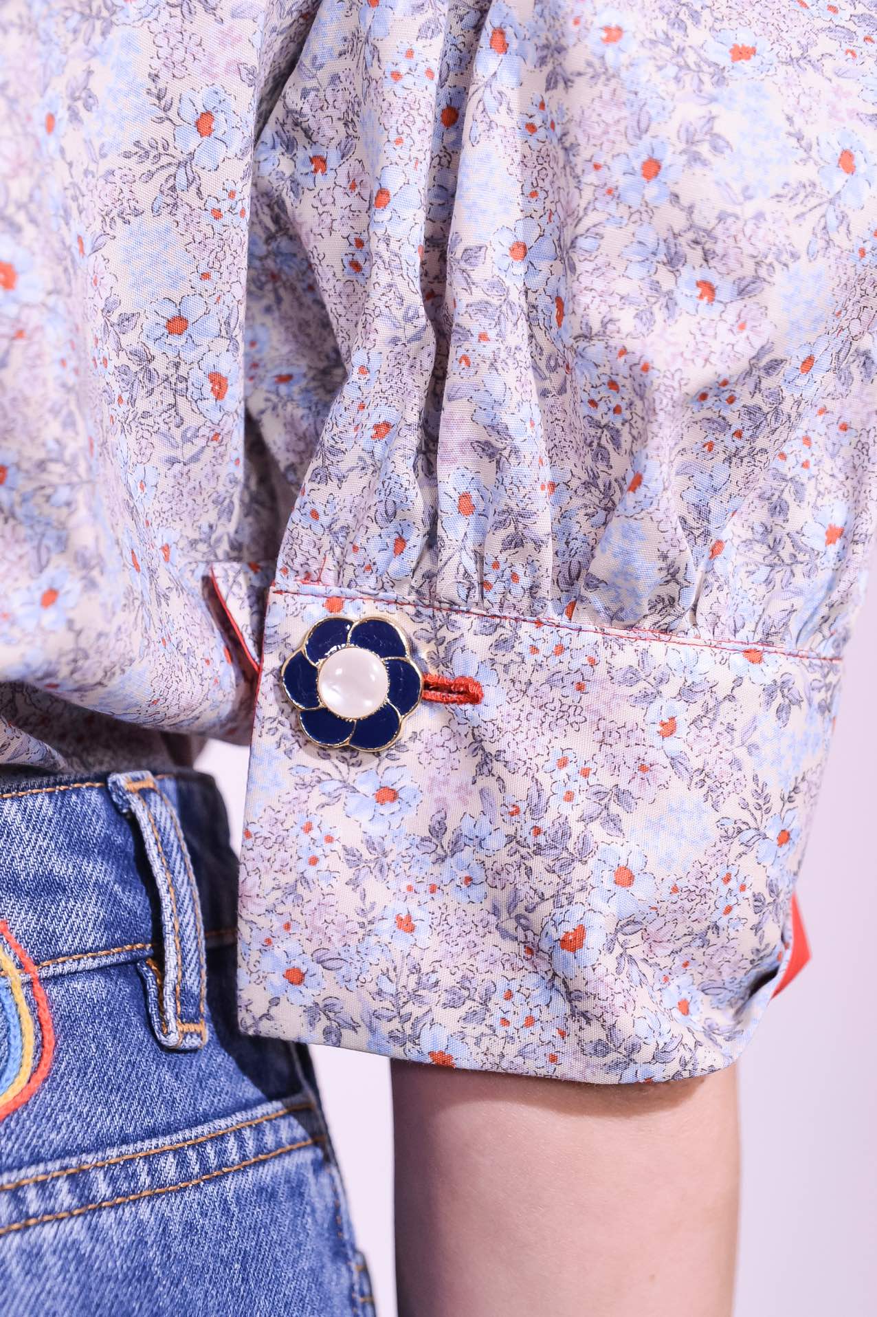 Model is wearing the Mirca Fantasia Liberty Blouse by House of Woven Stories: a lightweight cotton blouse with Liberty floral print, puffed sleeves, bright coral trims, a vintage collar button, and a matching fabric tie for styling.