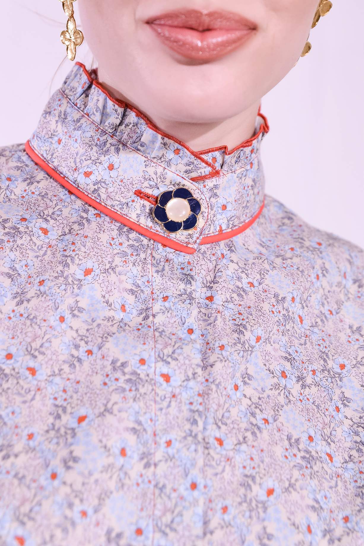 Model is wearing the Mirca Fantasia Liberty Blouse by House of Woven Stories: a lightweight cotton blouse with Liberty floral print, puffed sleeves, bright coral trims, a vintage collar button, and a matching fabric tie for styling.