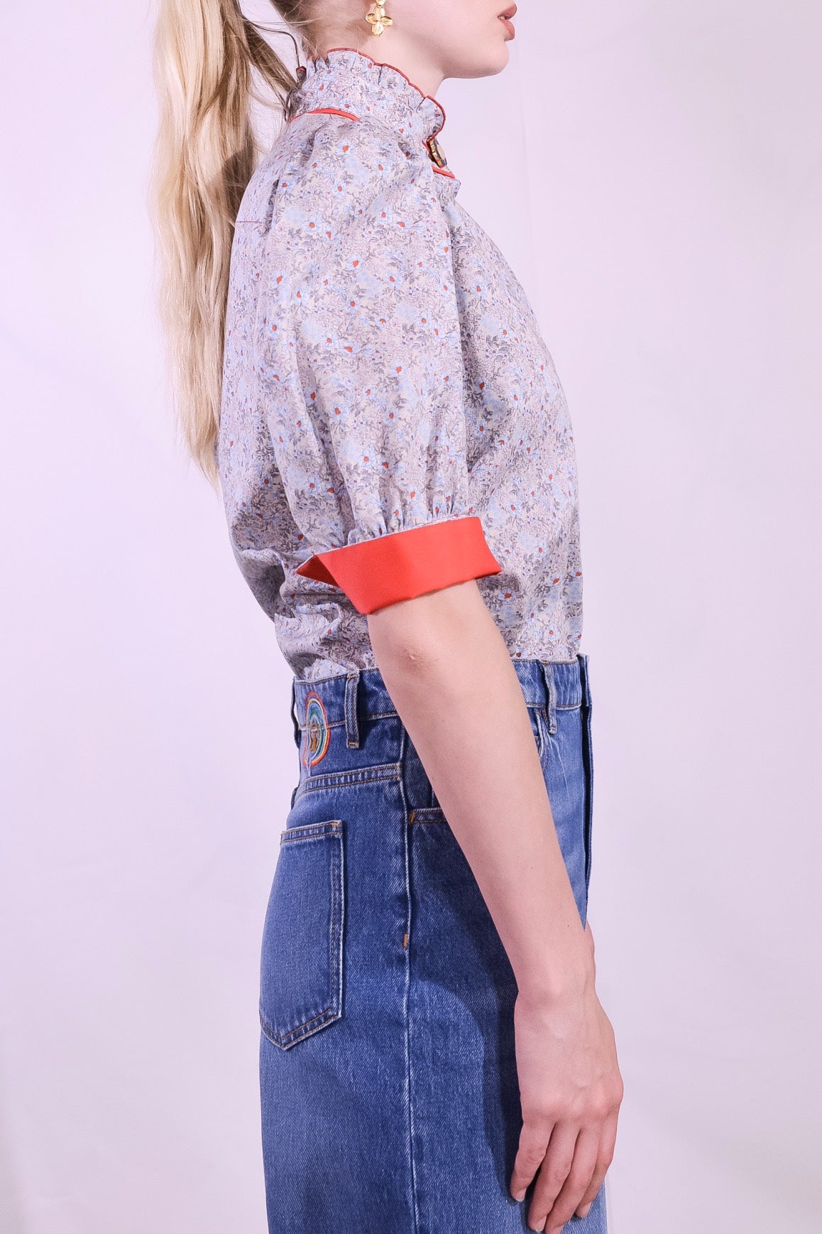 Model is wearing the Mirca Fantasia Liberty Blouse by House of Woven Stories: a lightweight cotton blouse with Liberty floral print, puffed sleeves, bright coral trims, a vintage collar button, and a matching fabric tie for styling.