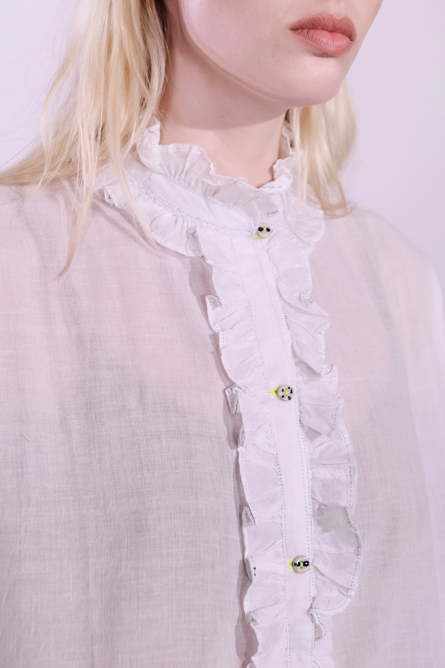 White pure cotton shirt by Injiri with cobalt ruffle stitching and yellow buttons, handmade and sustainable. Available at House of Woven Stories.