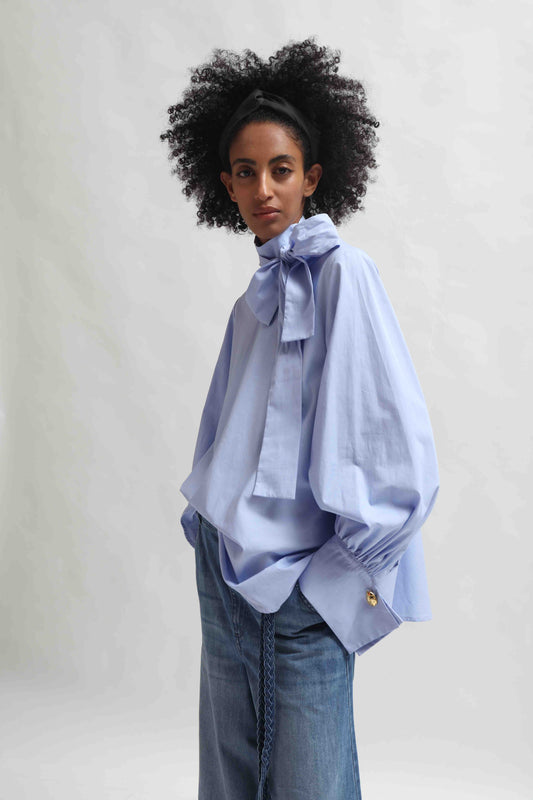Sky Blue organic cotton blouse by House of Woven Stories, featuring a signature adjustable tie-neck detail. Ethically made in Italy in small batches from soft, premium poplin.