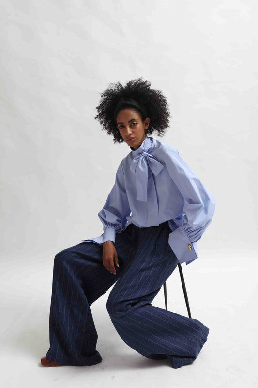 Sky Blue organic cotton blouse by House of Woven Stories, featuring a signature adjustable tie-neck detail. Ethically made in Italy in small batches from soft, premium poplin.