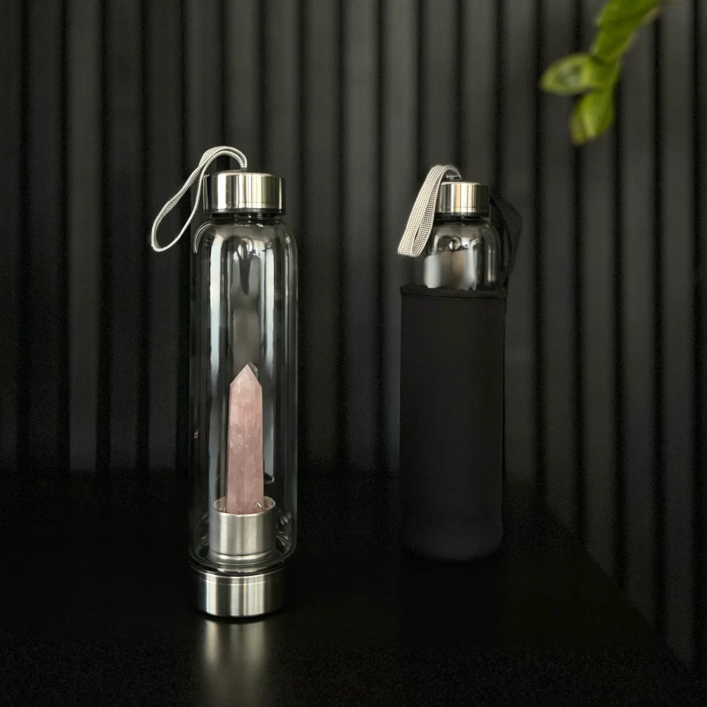Rose Quartz Crystal Water Bottle by The Goddess Collective, featuring a natural crystal obelisk inside a glass bottle with stainless steel lids and carry sleeve.