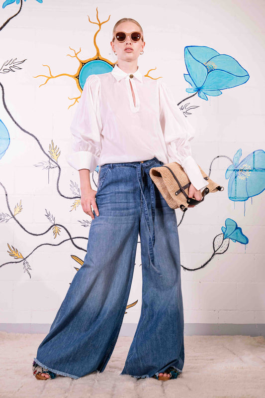 Model is wearing a white V-neck cotton blouse with relaxed fit, wide cuffs, and vintage button detail by House of Woven Stories.