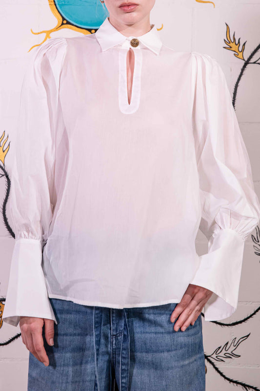 Model is wearing a white V-neck cotton blouse with relaxed fit, wide cuffs, and vintage button detail by House of Woven Stories.