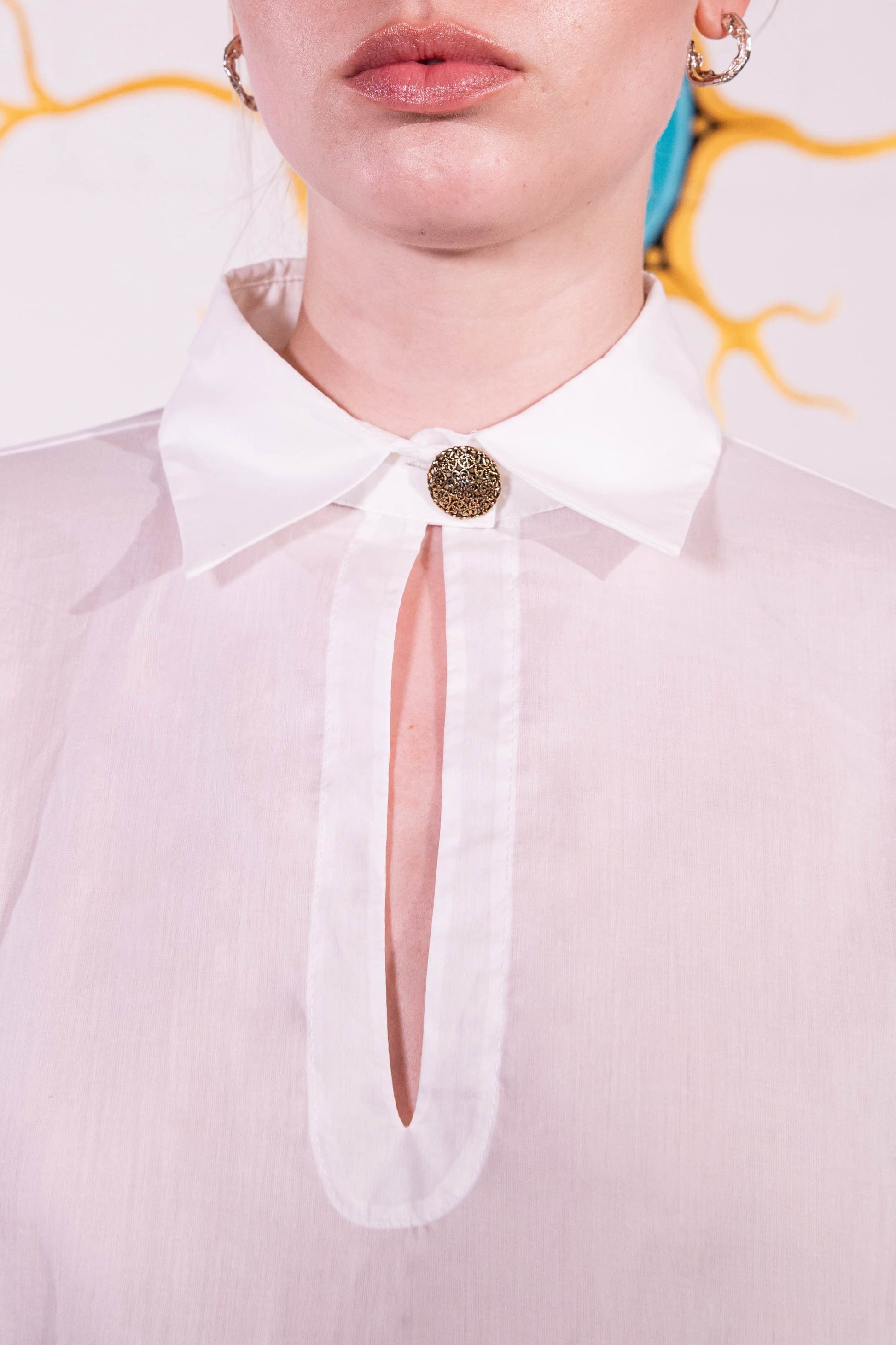 Model is wearing a white V-neck cotton blouse with relaxed fit, wide cuffs, and vintage button detail by House of Woven Stories.