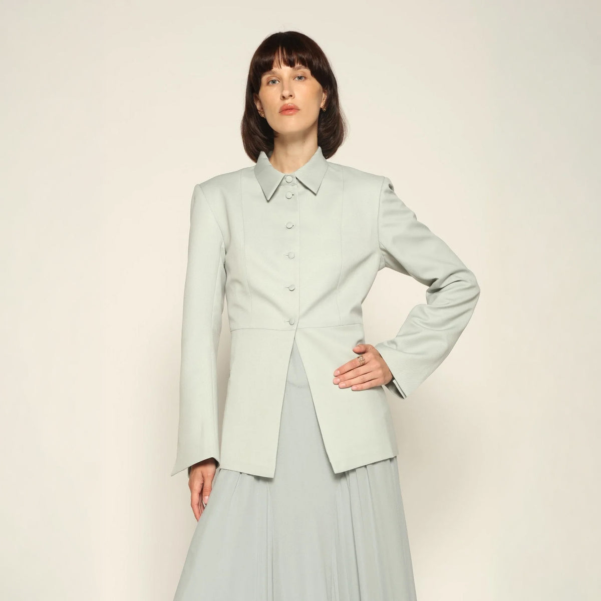 Model wearing a green tailored collared blazer by Abadia from the House of Nomad Stories collection, featuring a structured wool blend fabric, sharp collar, fitted silhouette, and clean minimal tailoring.
