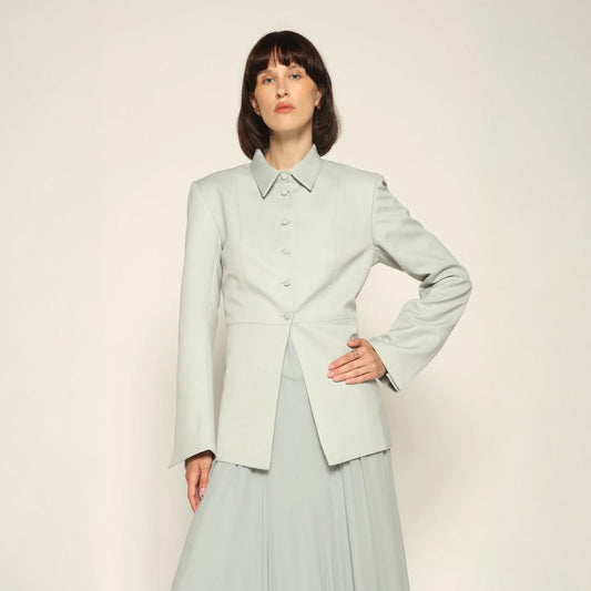 Model wearing a green tailored collared blazer by Abadia from the House of Nomad Stories collection, featuring a structured wool blend fabric, sharp collar, fitted silhouette, and clean minimal tailoring.