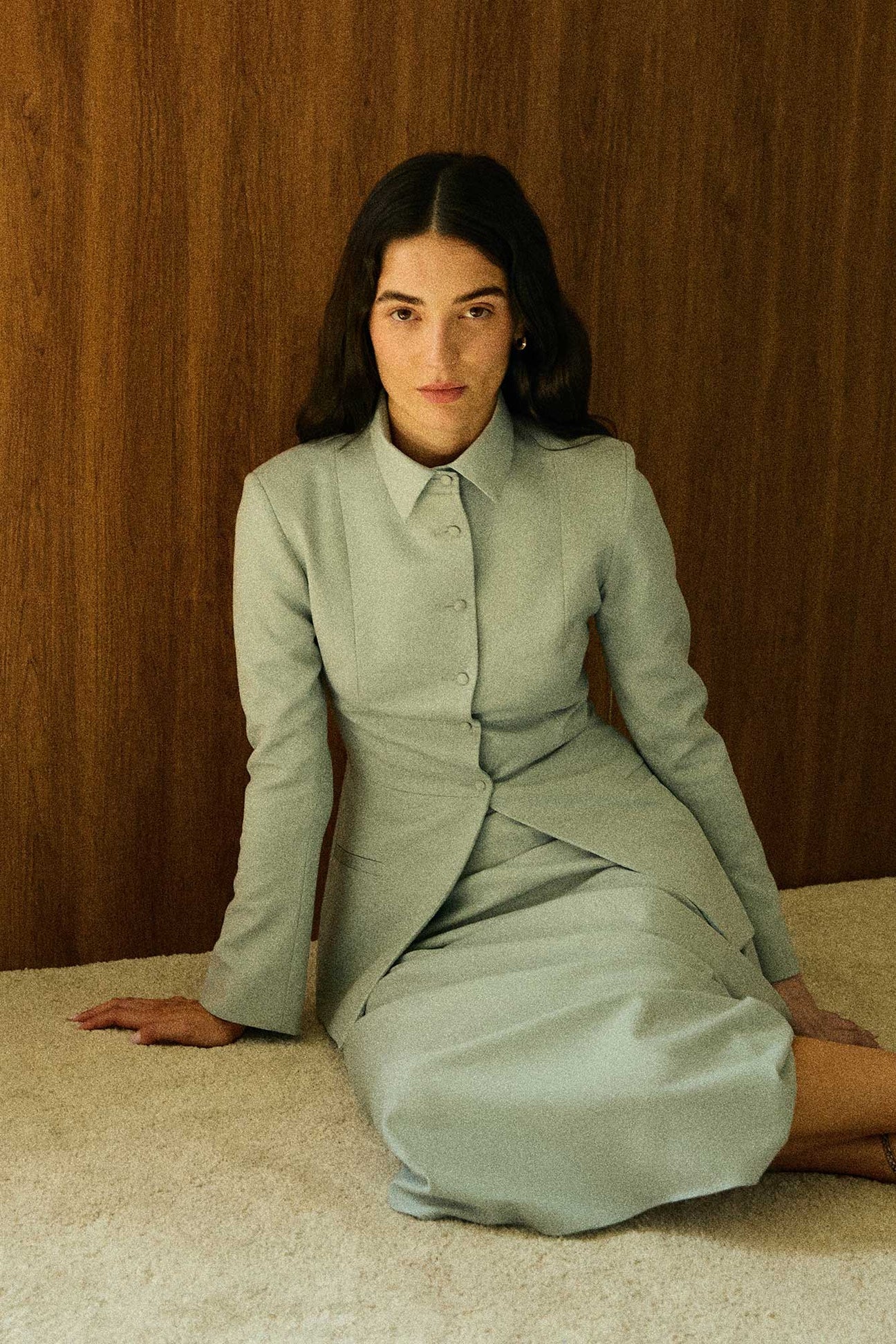 Model wearing a green tailored collared blazer by Abadia from the House of Nomad Stories collection, featuring a structured wool blend fabric, sharp collar, fitted silhouette, and clean minimal tailoring.
