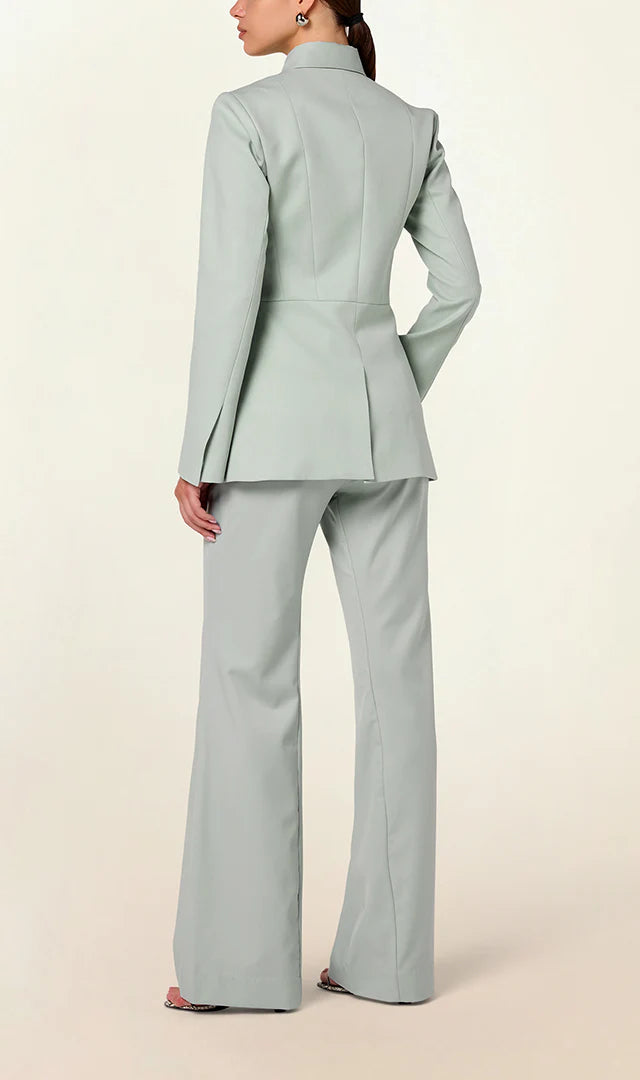 Model wearing a green tailored collared blazer by Abadia from the House of Nomad Stories collection, featuring a structured wool blend fabric, sharp collar, fitted silhouette, and clean minimal tailoring.