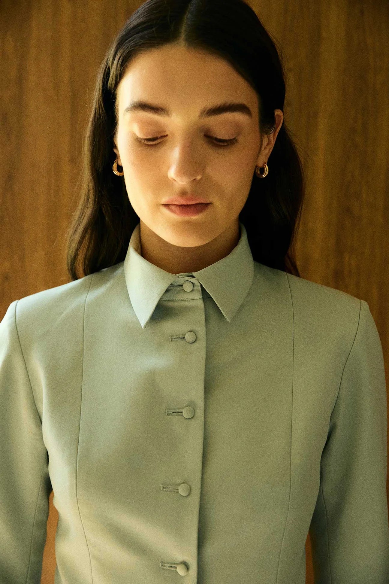 Model wearing a green tailored collared blazer by Abadia from the House of Nomad Stories collection, featuring a structured wool blend fabric, sharp collar, fitted silhouette, and clean minimal tailoring.