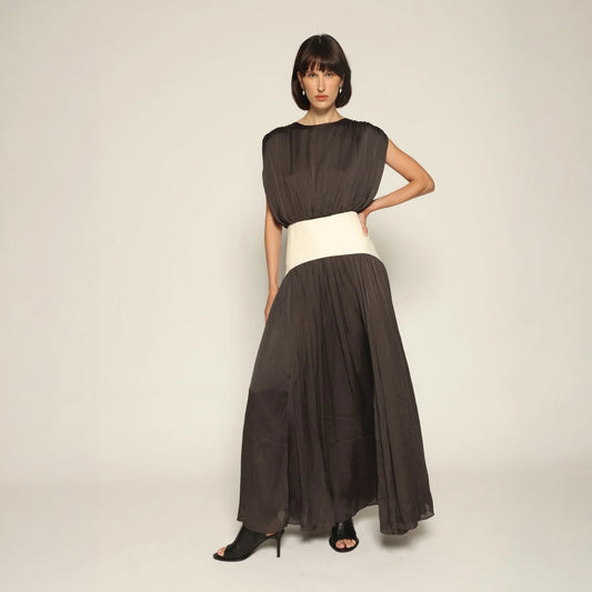 Model wearing a charcoal Suri Maxi Dress by Abadia from the House of Nomad Stories collection, featuring a sleeveless gathered bodice, defined waistband, and a soft flowing maxi silhouette.