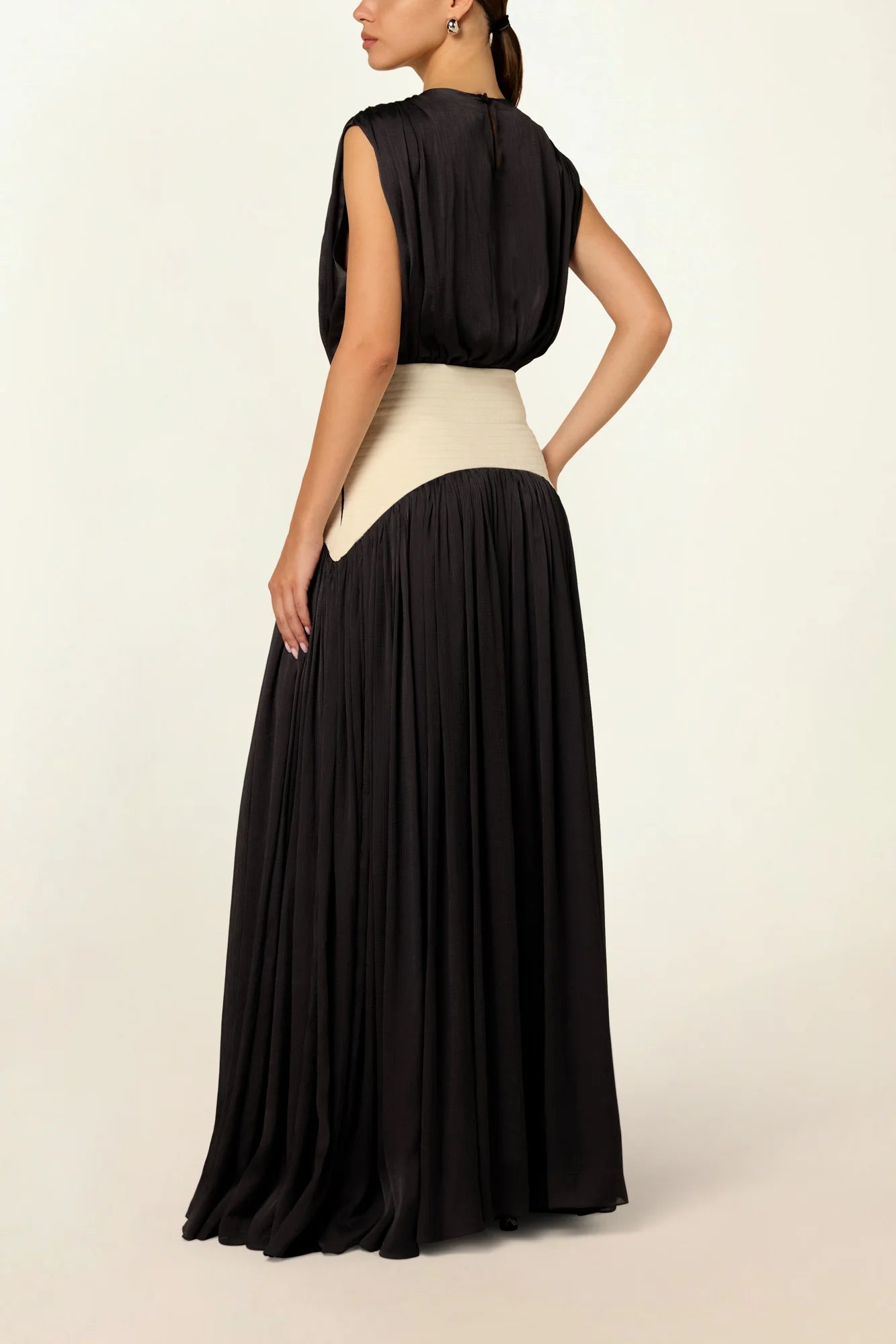 Model wearing a charcoal Suri Maxi Dress by Abadia from the House of Nomad Stories collection, featuring a sleeveless gathered bodice, defined waistband, and a soft flowing maxi silhouette.