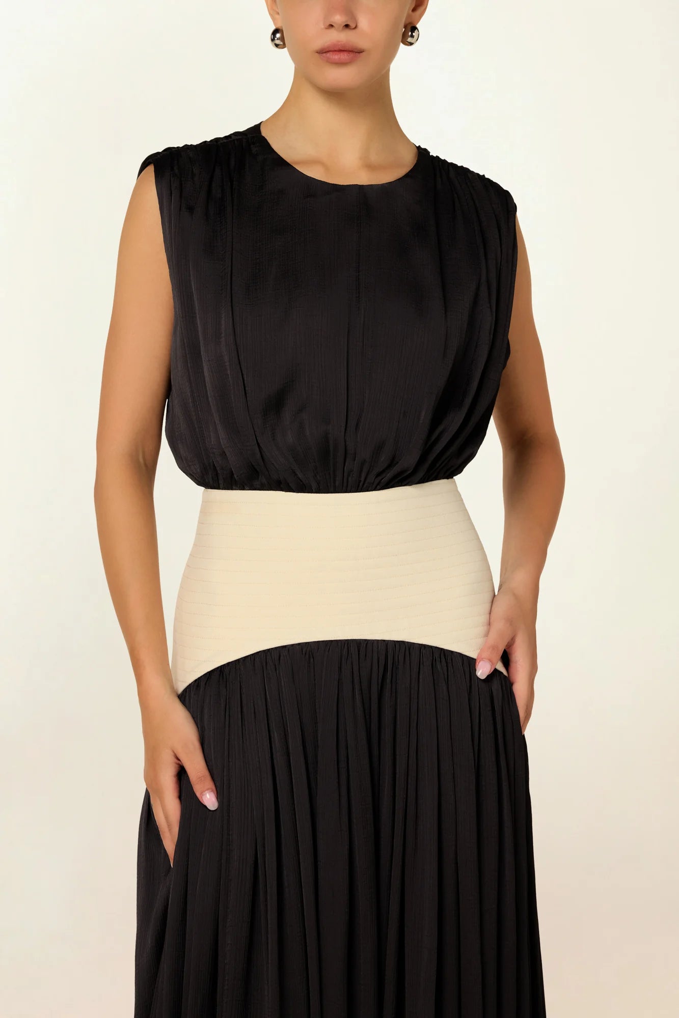 Model wearing a charcoal Suri Maxi Dress by Abadia from the House of Nomad Stories collection, featuring a sleeveless gathered bodice, defined waistband, and a soft flowing maxi silhouette.