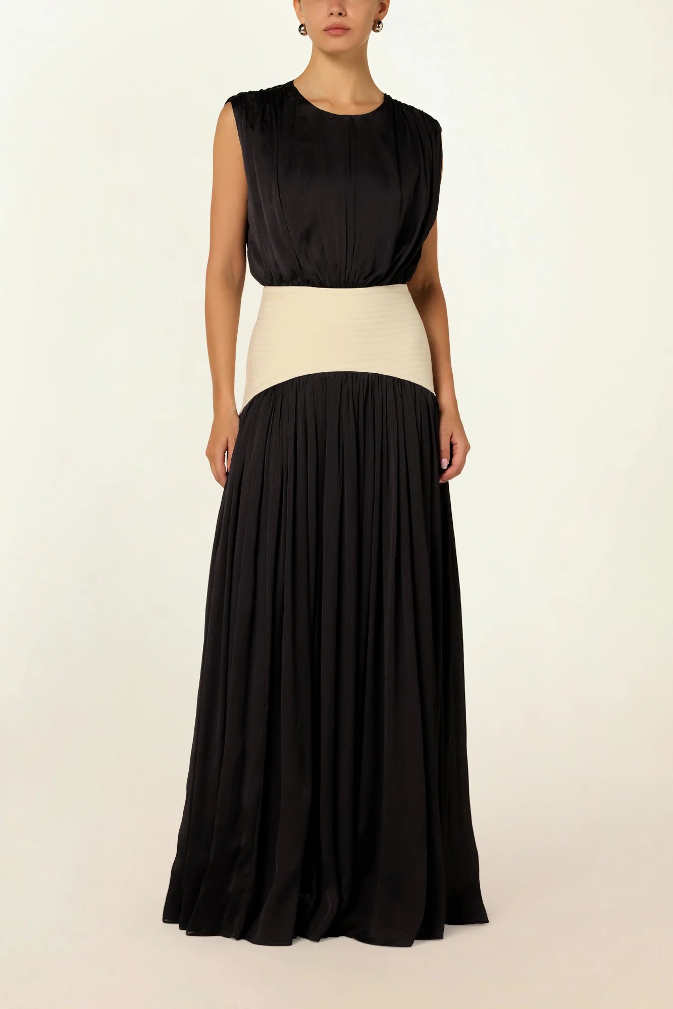 Model wearing a charcoal Suri Maxi Dress by Abadia from the House of Nomad Stories collection, featuring a sleeveless gathered bodice, defined waistband, and a soft flowing maxi silhouette.
