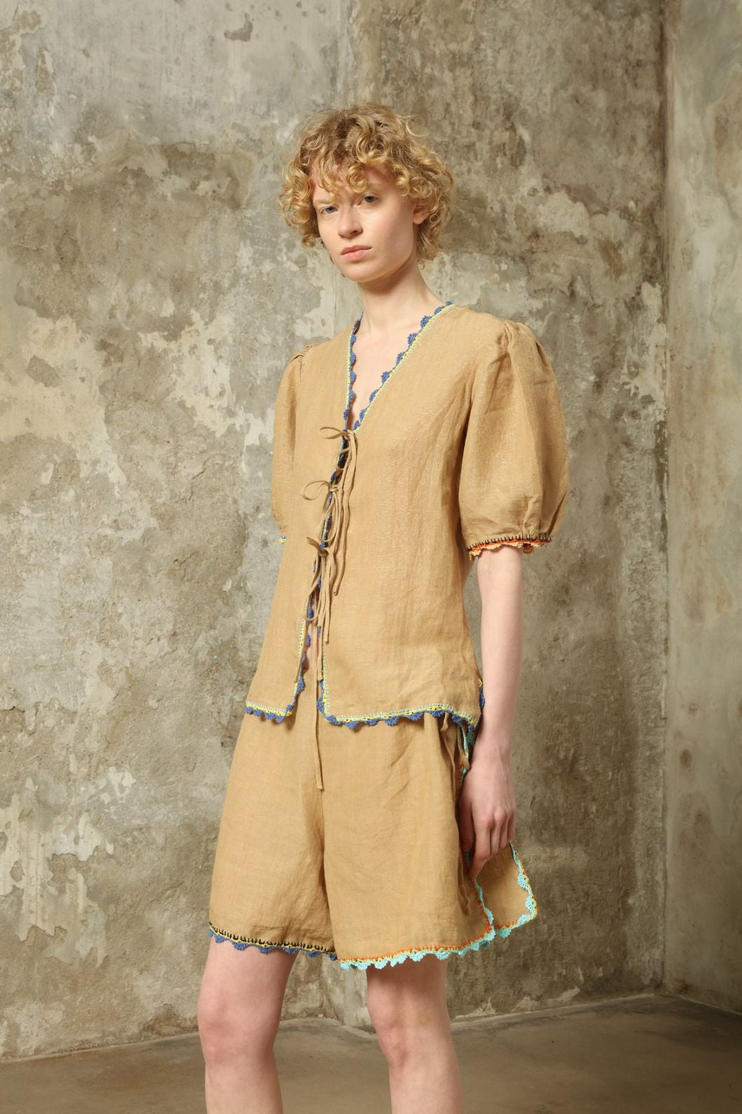 Model is wearing the Agata Beige Linen Set by Supernaturae x HONS in warm sandy beige botanical-dyed linen, featuring a refined two-piece silhouette with structured yet relaxed tailoring. This sustainable slow fashion set shows natural tonal variations unique to each garment, crafted through small-batch production in Mexico using ancestral techniques and natural fibers, part of the House of Nomad Stories selection.