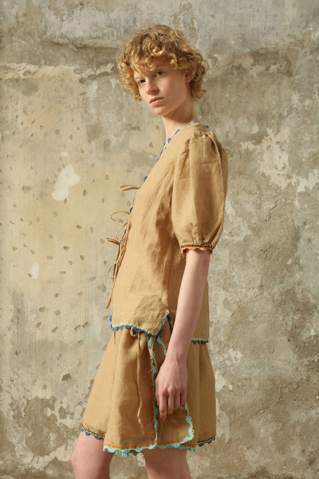 Model is wearing the Agata Beige Linen Set by Supernaturae x HONS in warm sandy beige botanical-dyed linen, featuring a refined two-piece silhouette with structured yet relaxed tailoring. This sustainable slow fashion set shows natural tonal variations unique to each garment, crafted through small-batch production in Mexico using ancestral techniques and natural fibers, part of the House of Nomad Stories selection.