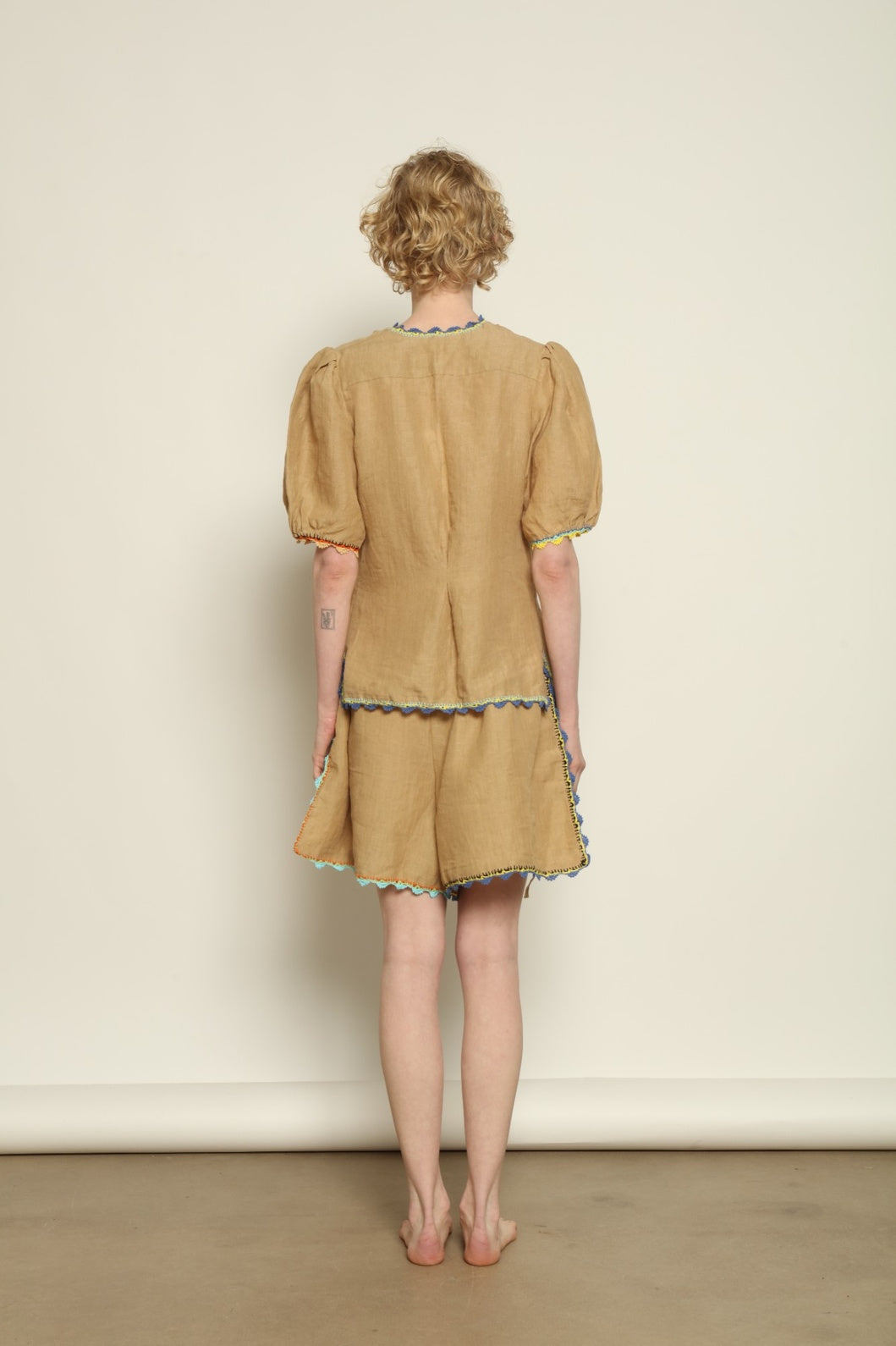 Model is wearing the Agata Beige Linen Set by Supernaturae x HONS in warm sandy beige botanical-dyed linen, featuring a refined two-piece silhouette with structured yet relaxed tailoring. This sustainable slow fashion set shows natural tonal variations unique to each garment, crafted through small-batch production in Mexico using ancestral techniques and natural fibers, part of the House of Nomad Stories selection.