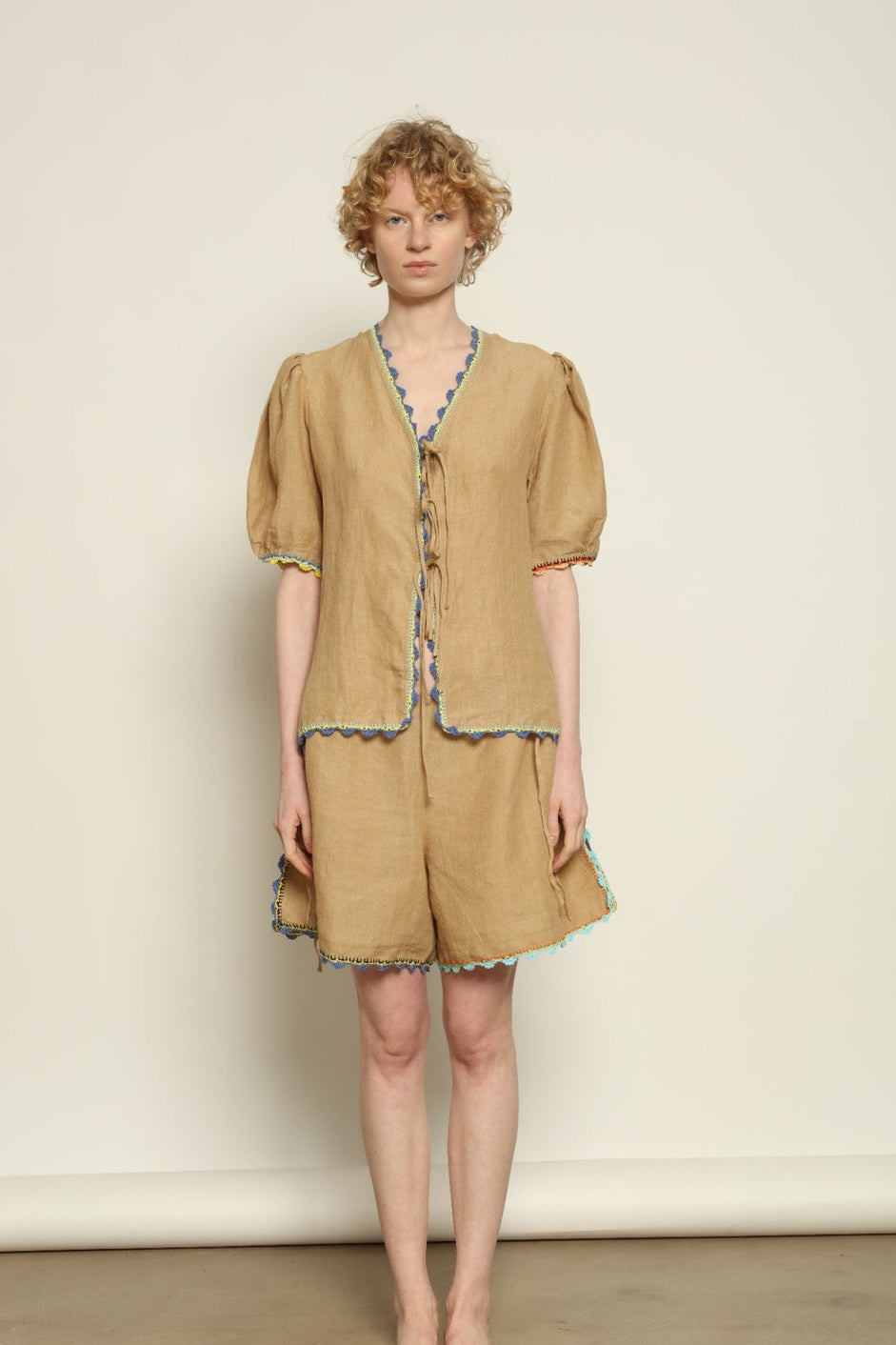 Model is wearing the Agata Beige Linen Set by Supernaturae x HONS in warm sandy beige botanical-dyed linen, featuring a refined two-piece silhouette with structured yet relaxed tailoring. This sustainable slow fashion set shows natural tonal variations unique to each garment, crafted through small-batch production in Mexico using ancestral techniques and natural fibers, part of the House of Nomad Stories selection.