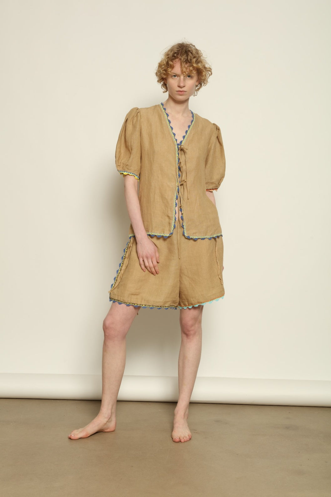 Model is wearing the Agata Beige Linen Set by Supernaturae x HONS in warm sandy beige botanical-dyed linen, featuring a refined two-piece silhouette with structured yet relaxed tailoring. This sustainable slow fashion set shows natural tonal variations unique to each garment, crafted through small-batch production in Mexico using ancestral techniques and natural fibers, part of the House of Nomad Stories selection.