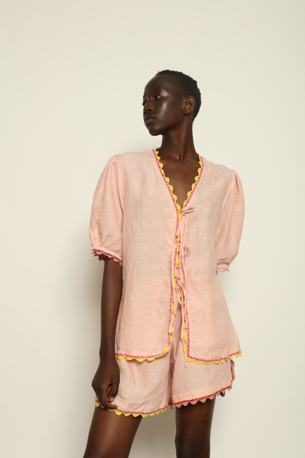 Model is wearing the Agata Pink Linen Set by Supernaturae x HONS, crafted in lightweight washed linen with soft botanical pink tones and delicate hand-crochet detailing. This sustainable summer capsule piece features a relaxed, breathable silhouette designed for effortless movement and timeless styling. Made in small-batch ethical production in Mexico, part of the House of Nomad Stories selection, worn by model 1.79m tall.