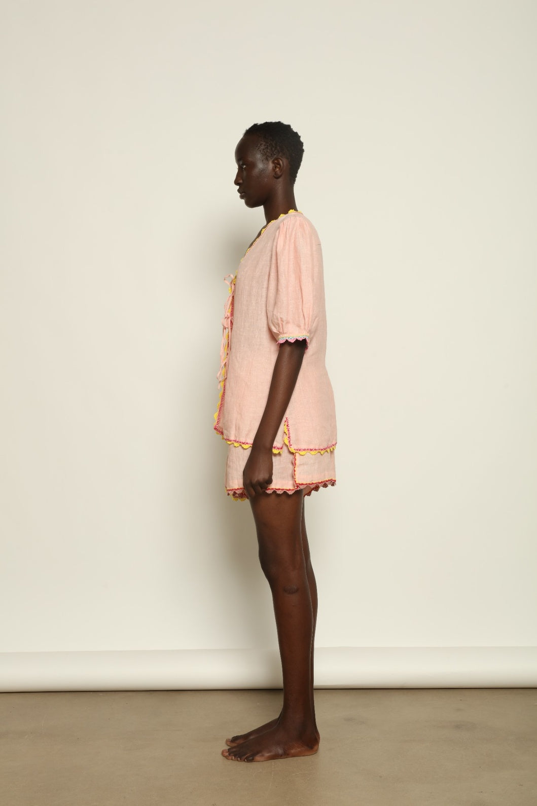Model is wearing the Agata Pink Linen Set by Supernaturae x HONS, crafted in lightweight washed linen with soft botanical pink tones and delicate hand-crochet detailing. This sustainable summer capsule piece features a relaxed, breathable silhouette designed for effortless movement and timeless styling. Made in small-batch ethical production in Mexico, part of the House of Nomad Stories selection, worn by model 1.79m tall.