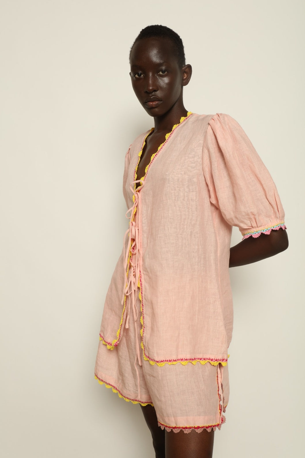 Model is wearing the Agata Pink Linen Set by Supernaturae x HONS, crafted in lightweight washed linen with soft botanical pink tones and delicate hand-crochet detailing. This sustainable summer capsule piece features a relaxed, breathable silhouette designed for effortless movement and timeless styling. Made in small-batch ethical production in Mexico, part of the House of Nomad Stories selection, worn by model 1.79m tall.
