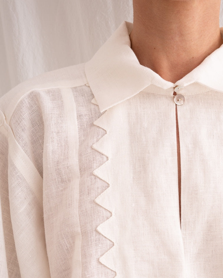 Model is wearing the Ancestral White Linen Shirt by Les Vacances d’Irina, a unisex handmade linen shirt with relaxed cut, open V-neckline, and natural shell buttons, crafted in Bucharest and available at House of Woven Stories.
