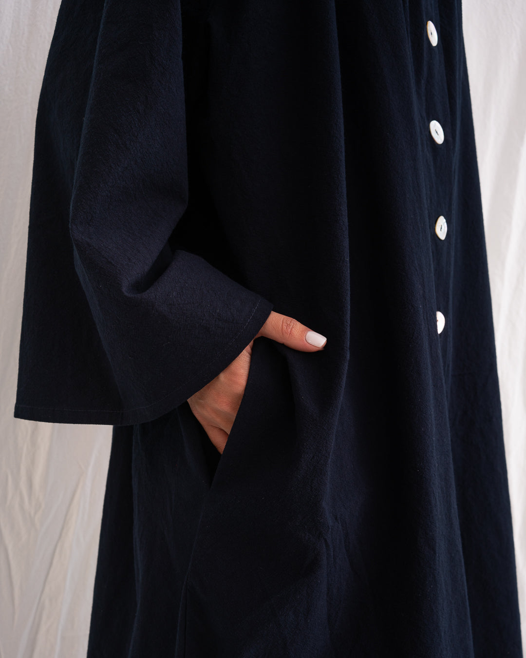 A Bigger Splash Cotton Dress by Les Vacances d’Irina, full-length long-sleeved maxi dress in ivory cotton with shell buttons, high collar, and hidden side pockets, handmade in Romania.