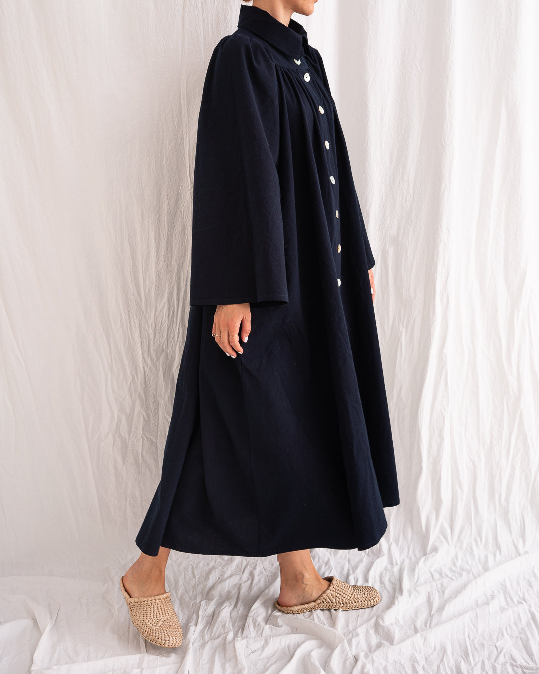 A Bigger Splash Cotton Dress by Les Vacances d’Irina, full-length long-sleeved maxi dress in ivory cotton with shell buttons, high collar, and hidden side pockets, handmade in Romania.