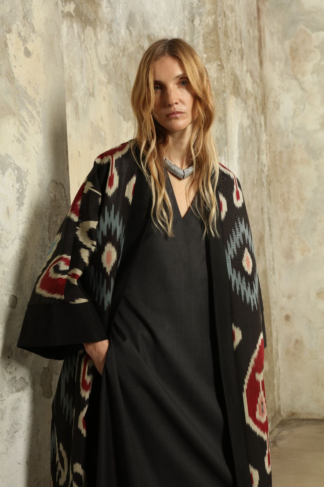 Model is wearing the Aura XL Ikat Silk Coat by Aleksandra Viktor, part of House of Woven Stories collection, handwoven Uzbek ikat silk coat with XL silhouette, expressive ikat motifs, and deep red lining
