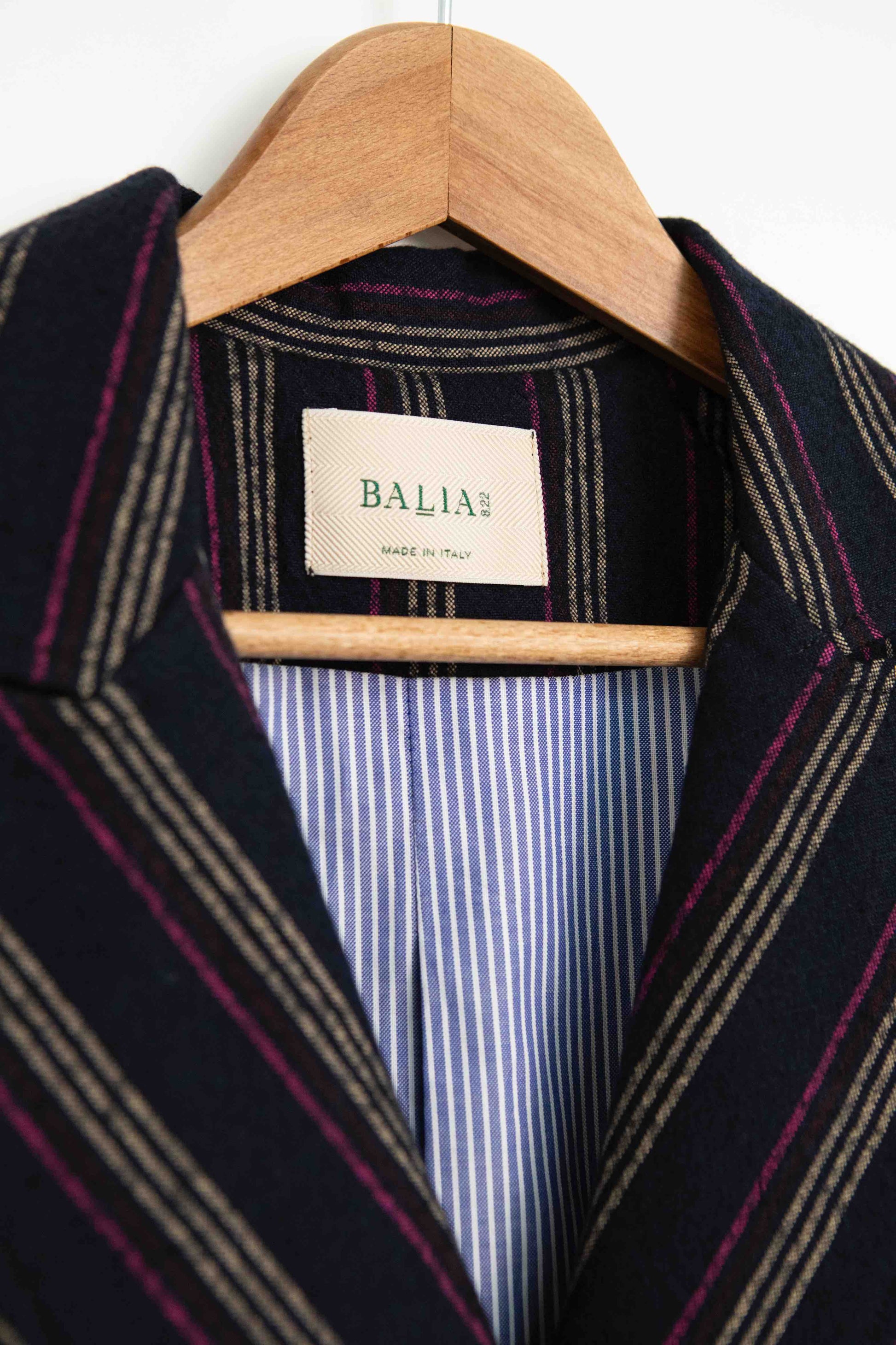 Model is wearing Balia 8.22 navy blue striped blazer, double-breasted, tailored from virgin wool and cotton, Italian craftsmanship, luxury womenswear, formal and casual styling, part of House of Woven Stories curated selection.
