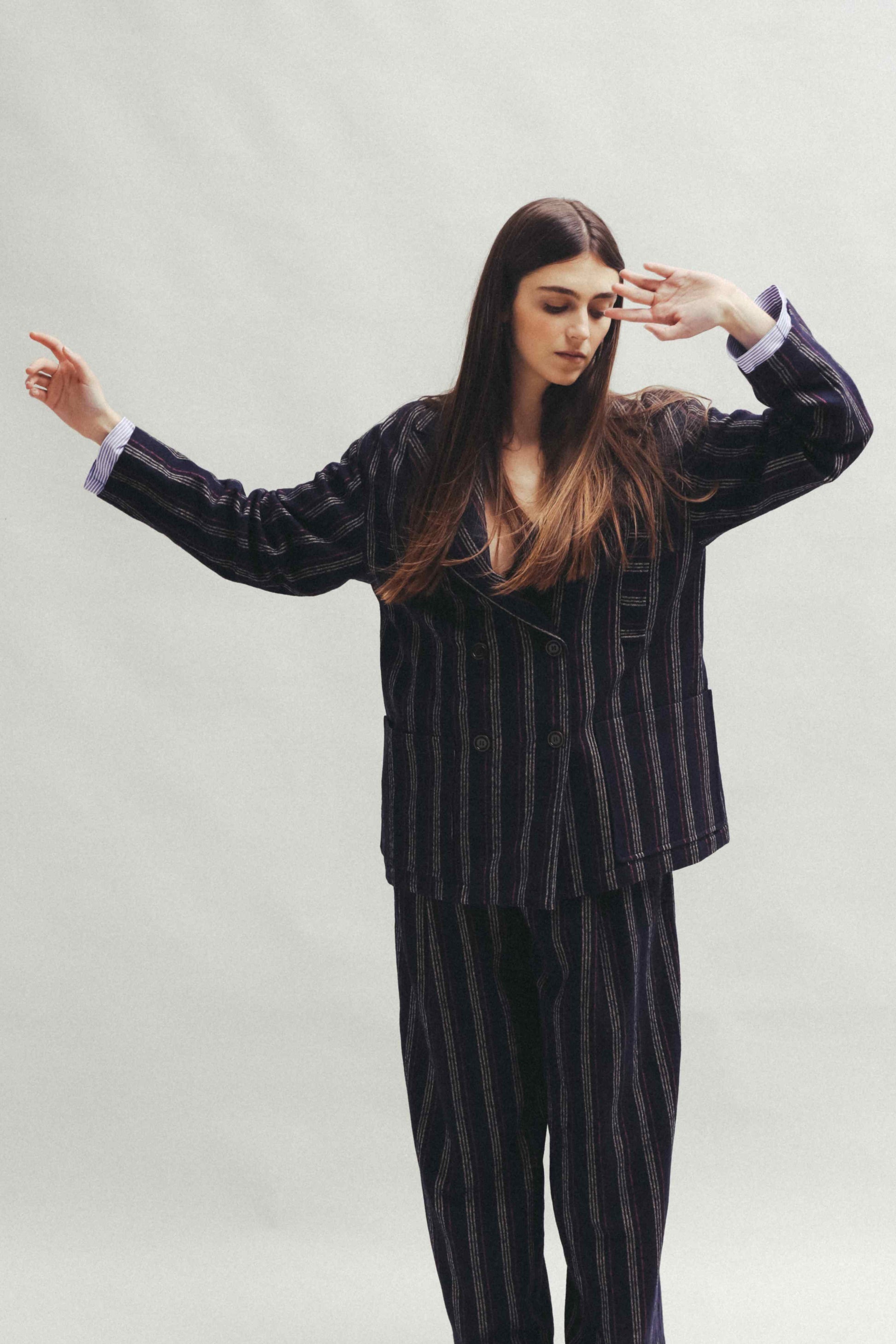 Model is wearing Balia 8.22 navy blue striped trousers made from virgin wool and cotton, tailored fit, Italian craftsmanship, part of House of Woven Stories selection.