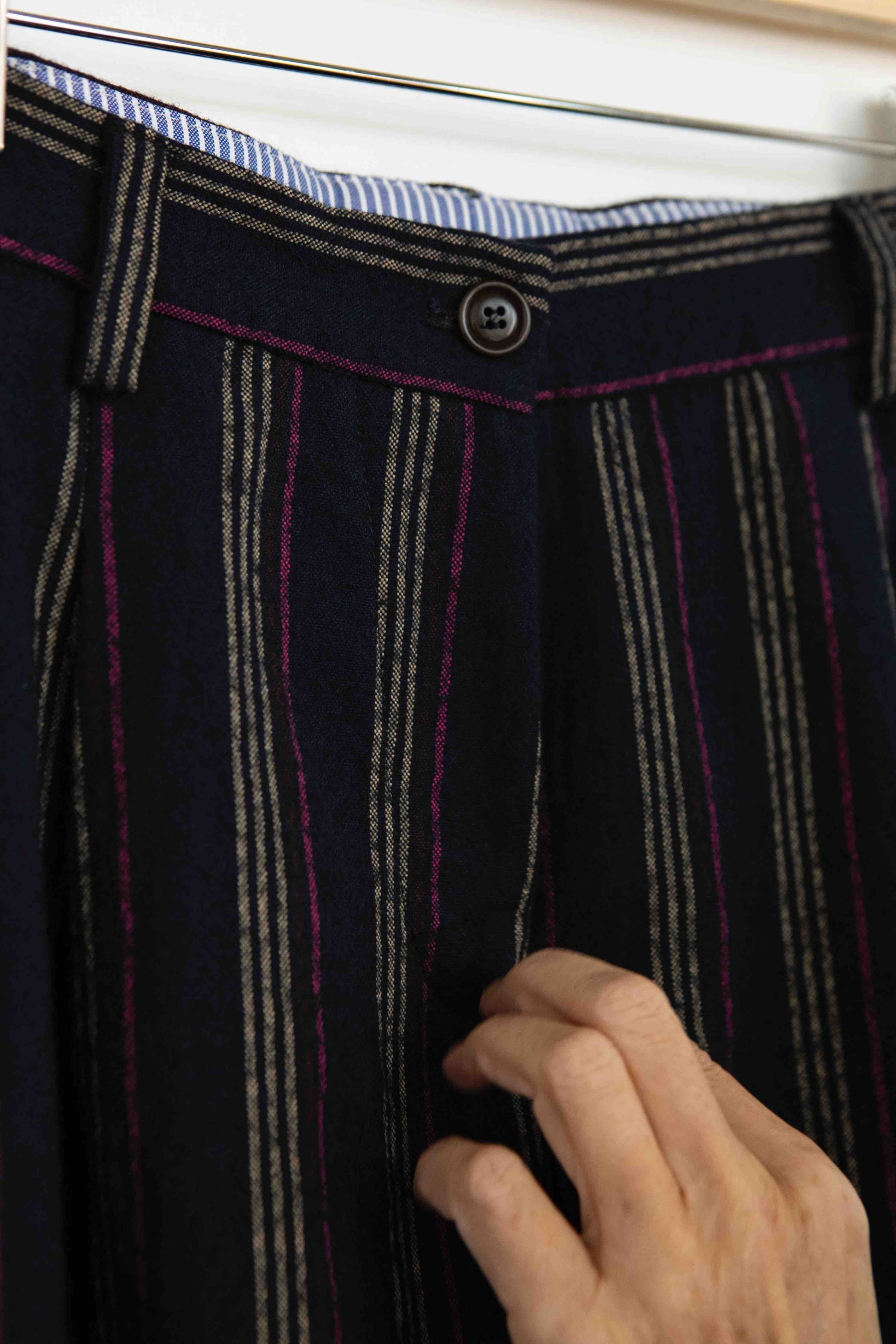 Model is wearing Balia 8.22 navy blue striped trousers made from virgin wool and cotton, tailored fit, Italian craftsmanship, part of House of Woven Stories selection.