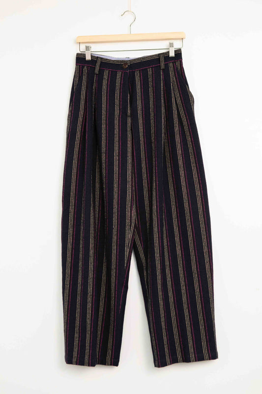 Model is wearing Balia 8.22 navy blue striped trousers made from virgin wool and cotton, tailored fit, Italian craftsmanship, part of House of Woven Stories selection.