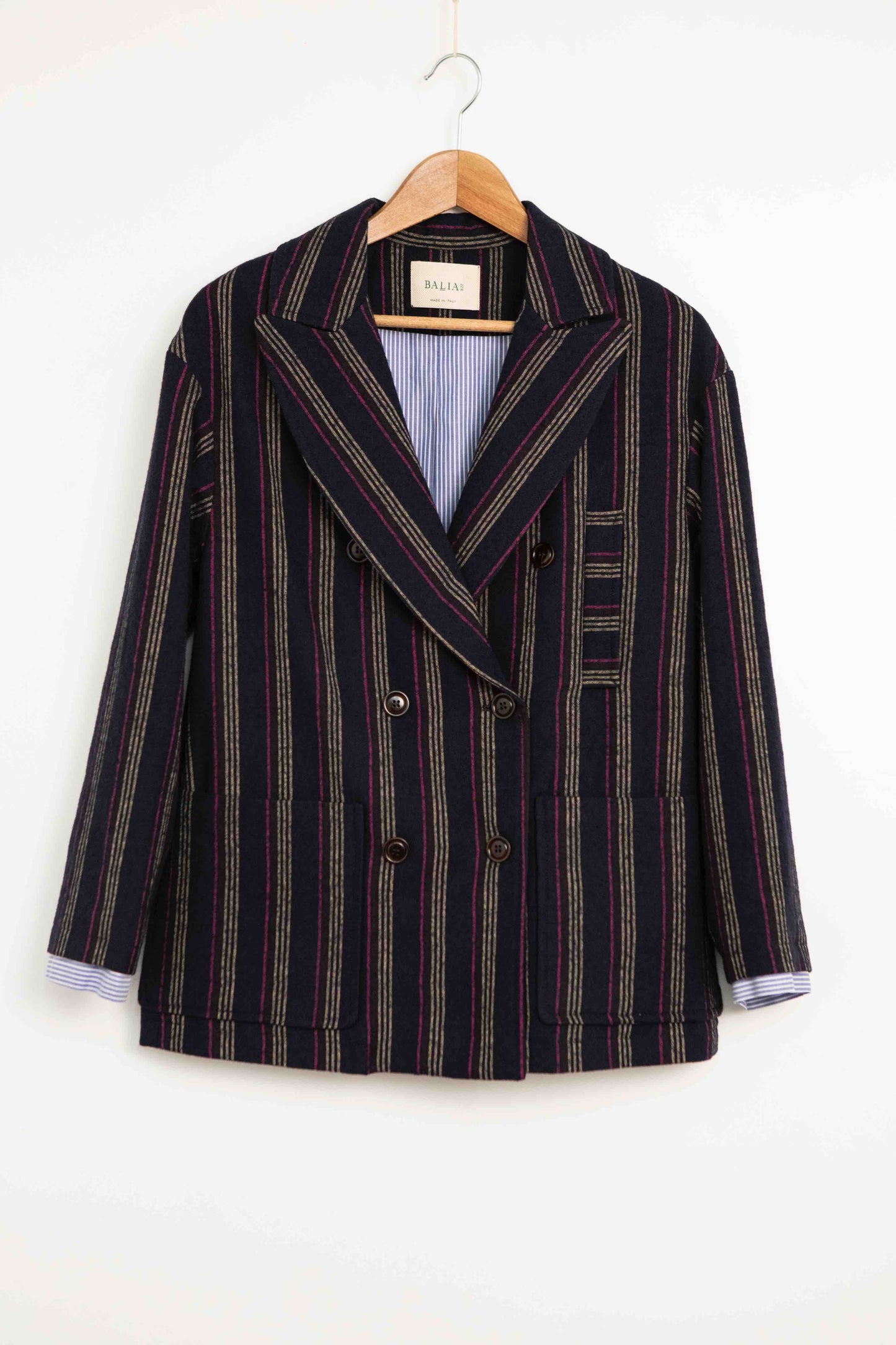 Model is wearing Balia 8.22 navy blue striped blazer, double-breasted, tailored from virgin wool and cotton, Italian craftsmanship, luxury womenswear, formal and casual styling, part of House of Woven Stories curated selection.