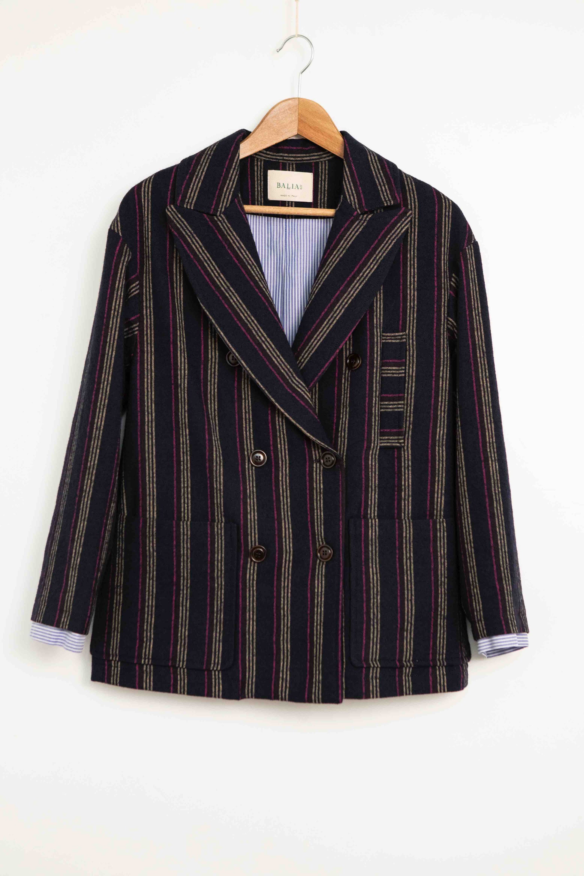 Model is wearing Balia 8.22 navy blue striped blazer, double-breasted, tailored from virgin wool and cotton, Italian craftsmanship, luxury womenswear, formal and casual styling, part of House of Woven Stories curated selection.