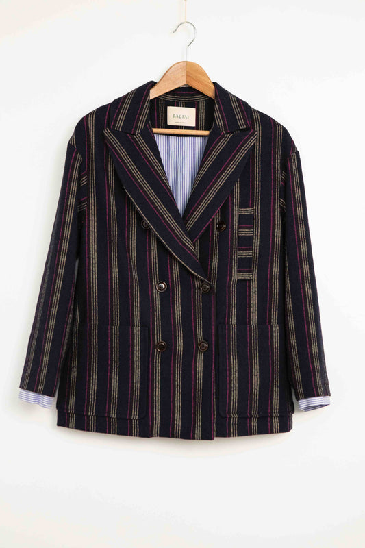 Model is wearing Balia 8.22 navy blue striped blazer, double-breasted, tailored from virgin wool and cotton, Italian craftsmanship, luxury womenswear, formal and casual styling, part of House of Woven Stories curated selection.