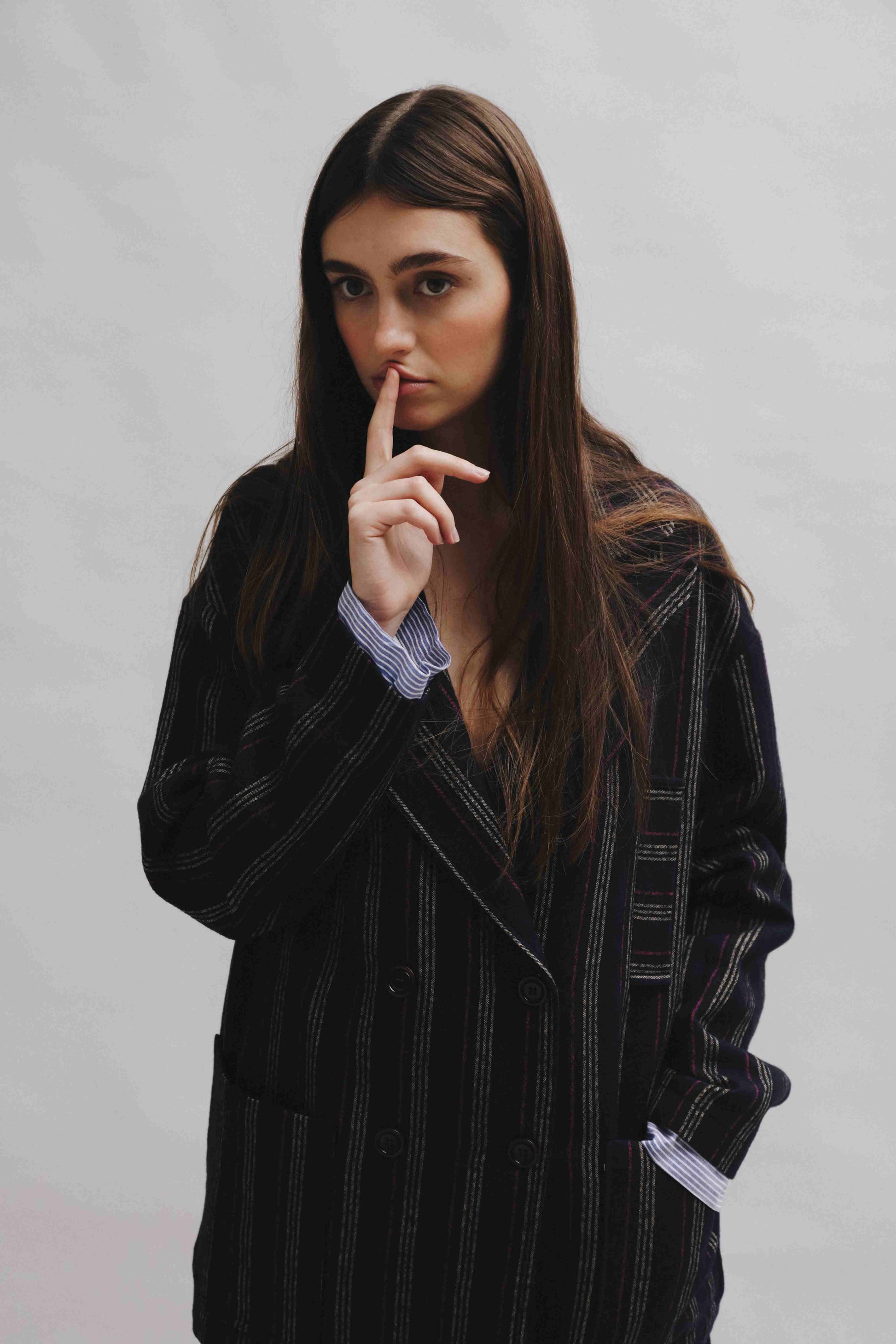 Model is wearing Balia 8.22 navy blue striped blazer, double-breasted, tailored from virgin wool and cotton, Italian craftsmanship, luxury womenswear, formal and casual styling, part of House of Woven Stories curated selection.