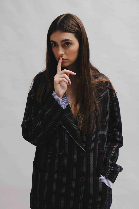 Model is wearing Balia 8.22 navy blue striped blazer, double-breasted, tailored from virgin wool and cotton, Italian craftsmanship, luxury womenswear, formal and casual styling, part of House of Woven Stories curated selection.