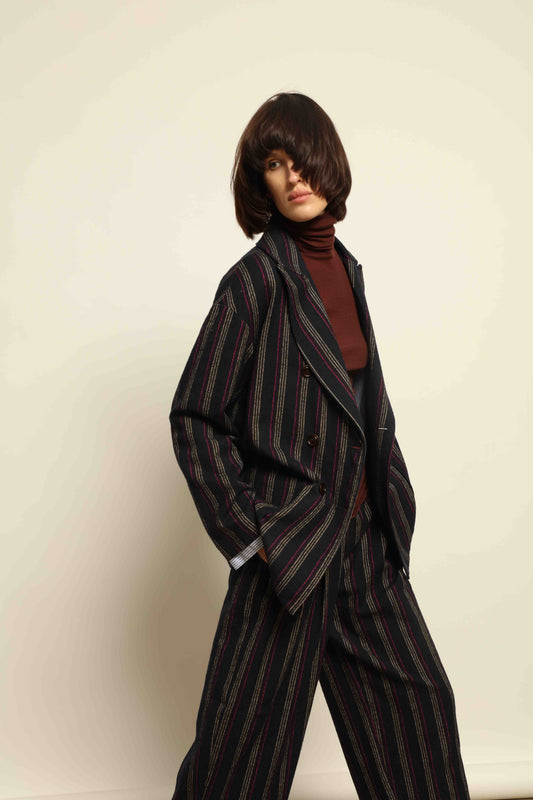 Model is wearing Balia 8.22 navy blue striped trousers made from virgin wool and cotton, tailored fit, Italian craftsmanship, part of House of Woven Stories selection.