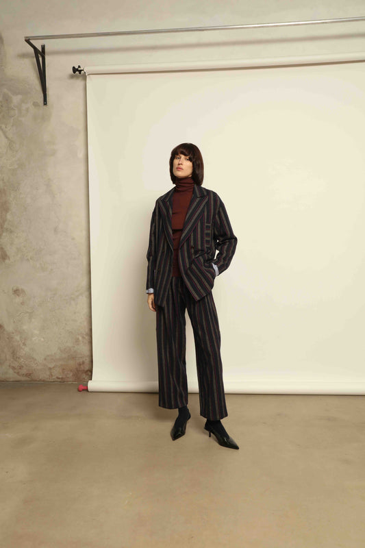 Model is wearing Balia 8.22 navy blue striped trousers made from virgin wool and cotton, tailored fit, Italian craftsmanship, part of House of Woven Stories selection.