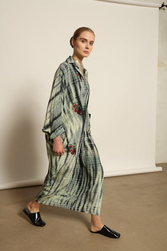 Model is wearing the Barcelona Stone Shade Dress by House of Woven Stories, crafted from 100% pure silk with stone-toned tie-dye and delicate hand-embroidered flowers, featuring a relaxed silhouette and soft collar for artistic, effortless elegance.