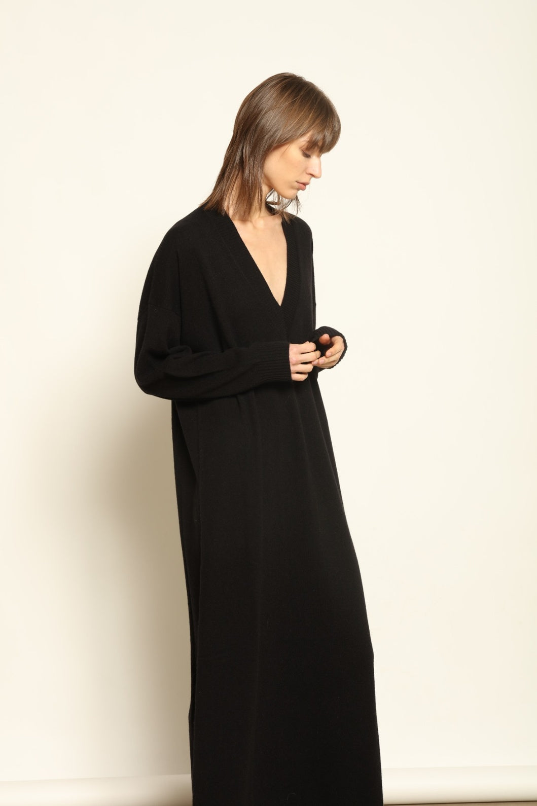 Model wearing the Black Katharina V-Neck Cashmere Maxi Dress by House of Woven Stories, crafted in Italy from 100% pure Inner Mongolia cashmere, featuring a flowing silhouette, soft drape, and timeless sustainable black knitwear design